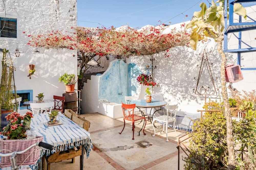 Sunlit patio at La Casa del Cine with bougainvillea overhead and tiled tables in the shade