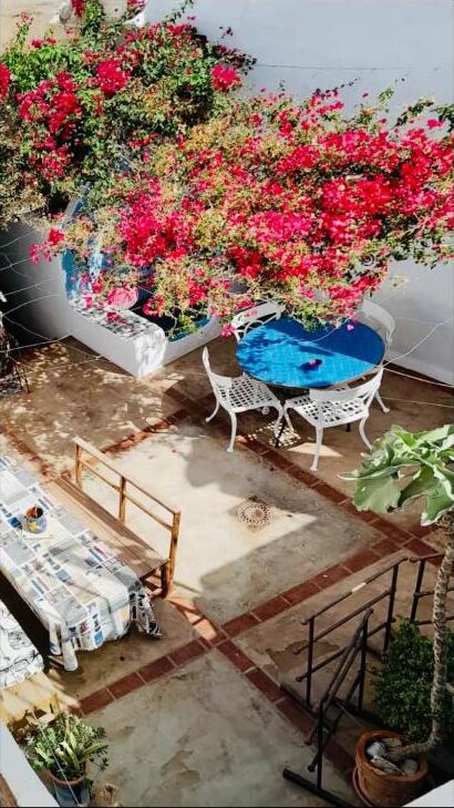 View down onto the patio with a blue tiled table beneath flowering bougainvillea
